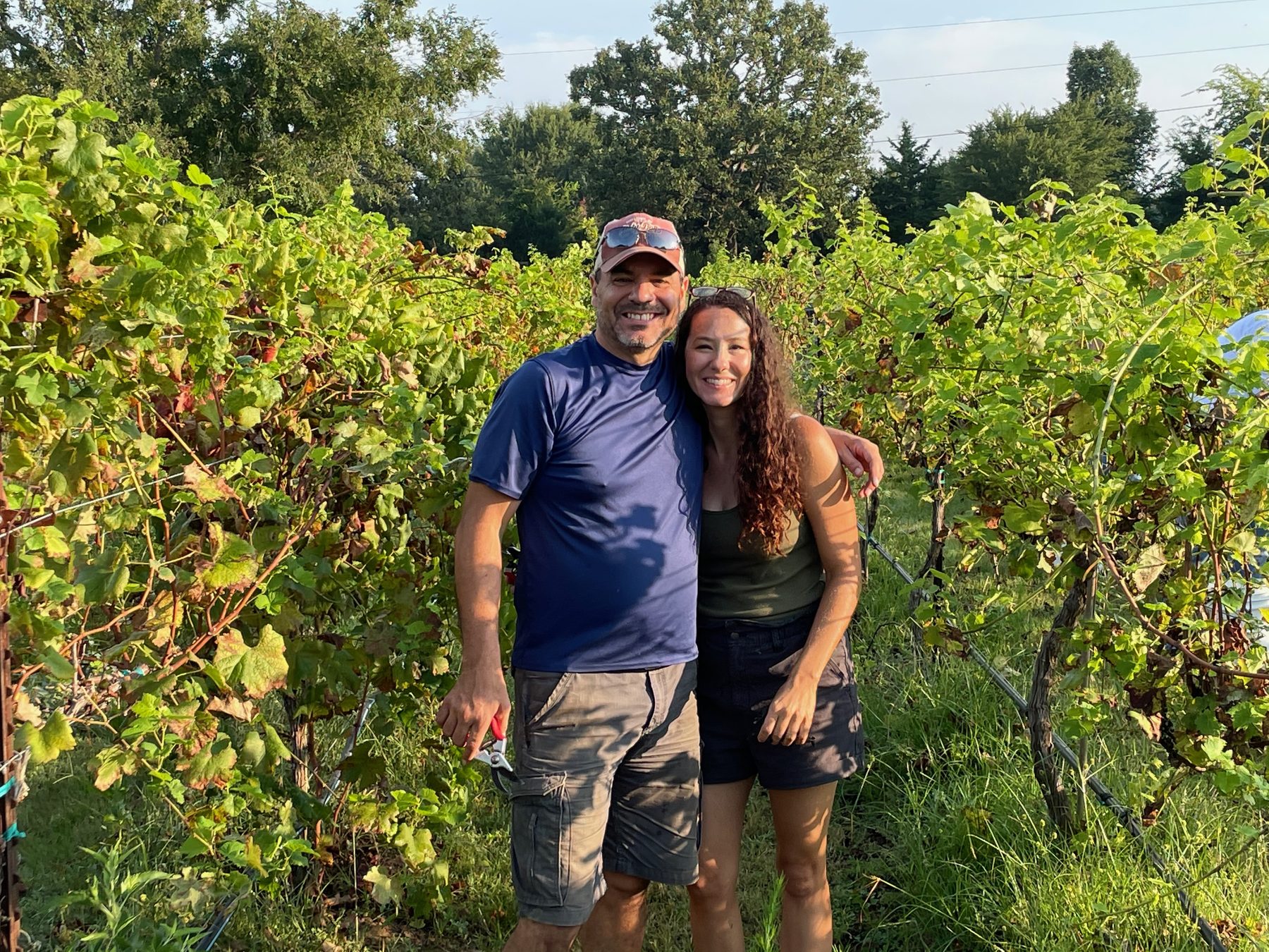 Mike and Heather smiling between the vine rows